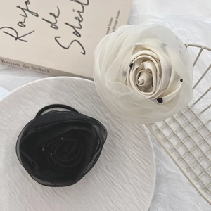 Close-up of elegant oversized chiffon flower hair ties in white polka dot and solid black