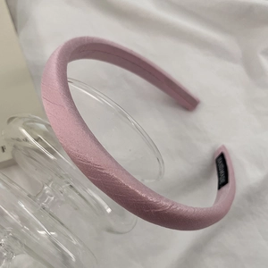 Detail of pink satin headband with handmade label showing delicate woven texture