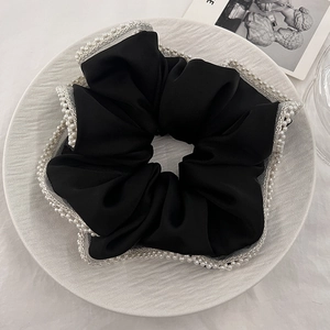 Detailed macro view of black satin hair scrunchie with double-row pearls and lace trim