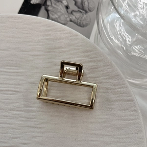 Macro view of a gold-toned hollow rectangular alloy hair claw with mirror-polished finish