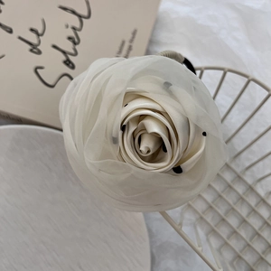 Close-up of cream white fabric rose hair tie with black polka dots in French vintage style