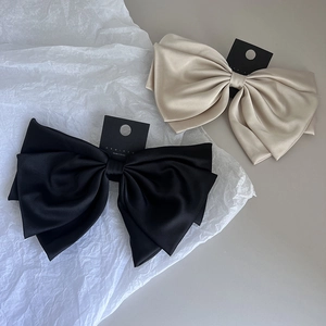 Detail of elegant black and champagne satin bow hair clips on minimalist display cards