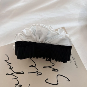 Detail of elegant black ribbon bow hair claw with white pleated ruffle fabric accents