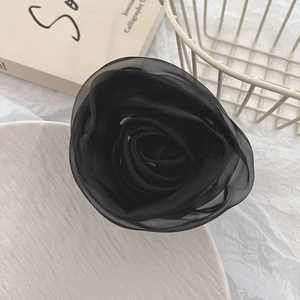 Detail of a large black layered fabric rose hair tie on an aesthetic white background