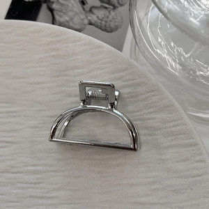 Detail of silver alloy mini hair claw clip with a polished finish and metal spring