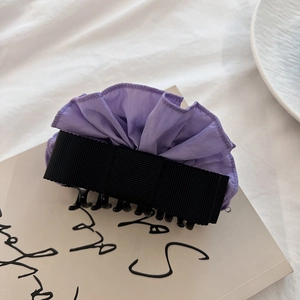 Detail of elegant lavender ruffled fabric hair claw clip with black ribbon bow decoration