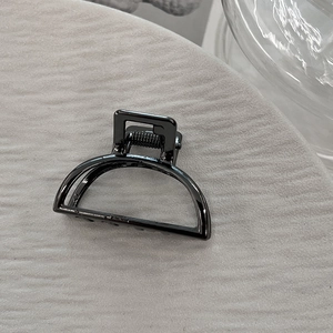 Close-up of small black metal hair claw clip with minimalist hollowed semi-circle design