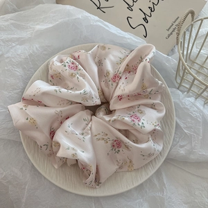 Detailed macro view of pink floral silk scrunchie on a decorative ceramic tray