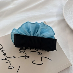 Detail view of a sky blue ruffled fabric and black ribbon bow hair claw clip