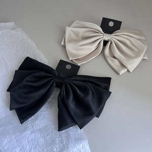 Close-up of elegant double-layered satin bow hair clips in black and champagne gold silk