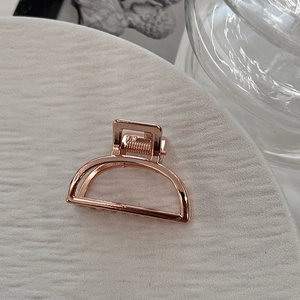 Detail shot of mini alloy hair claw in rose gold with a hollow D-shaped metal design