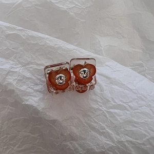 Détail de deux mini pinces à cheveux en acrylique avec fleurs corail et strass brillants