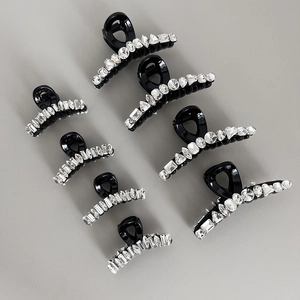 Détail de pinces à cheveux noires en deux tailles avec strass brillants sur fond gris