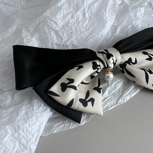 Detail of fabric bow hair clip with black satin, rabbit print, and pearl pendant