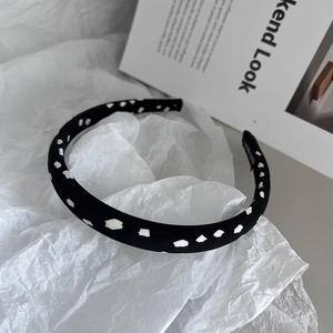 Detailed view of black fabric headband with white polka dots and handmade inner label