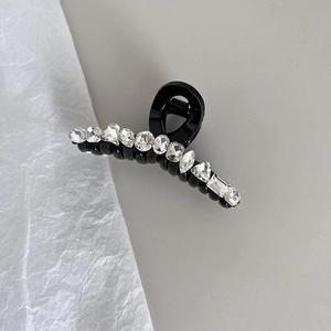 Détail d'une pince à cheveux noire en acrylique ornée de strass géométriques brillants