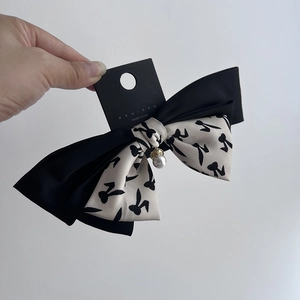 Detail of Korean-style bow hair clip with black heart patterns and pearl pendant