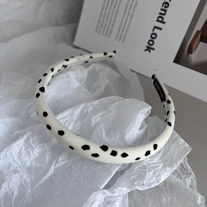 Detailed view of handmade black polka dot headband on minimalist magazine background