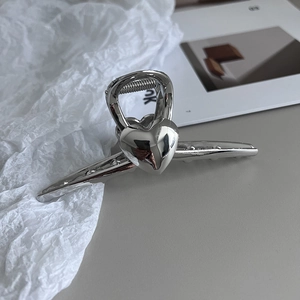 Détail macro d'une pince à cheveux cœur argentée avec finition miroir métallique