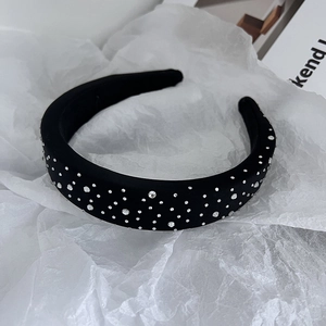 Close-up of black wide sponge headband with white rhinestones on crinkled paper