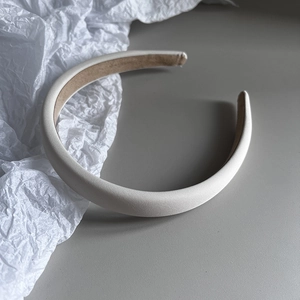 Close-up of padded cream fabric headband with soft texture and high-top design