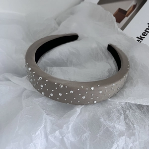 Detail of grey rhinestone padded headband with leather texture on artistic paper