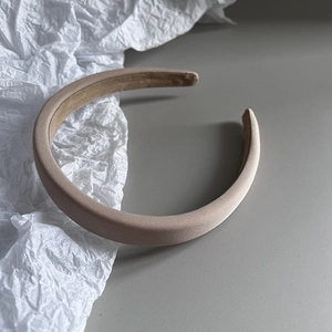 Detail of the thick champagne satin headband showing smooth silk fabric texture