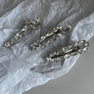 Détail macro de trois barrettes en alliage élégantes avec strass brillants sur papier