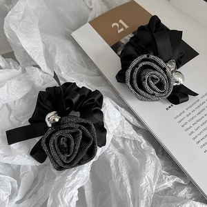 Close-up of black camellia hair scrunchie with houndstooth fabric rose and crystals