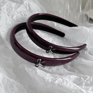 Detailed macro view of glossy burgundy headbands featuring silver metal bow accents