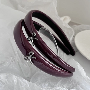 Elegant burgundy patent leather headbands with silver bow and pearls on white background