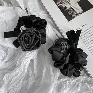 Elegant black satin scrunchie set with rose decor and ribbon on white paper