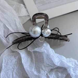 Detail of grey acrylic hair claw with silver texture beads and a metal brand tag