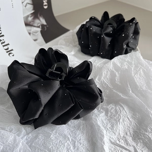 Detail of black satin cloud hair claw clip with sparkling rhinestones and ruched texture