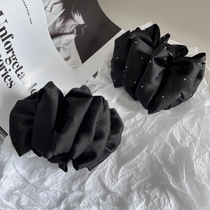 Elegant set of two black pleated fabric hair claws with subtle sparkle on white background