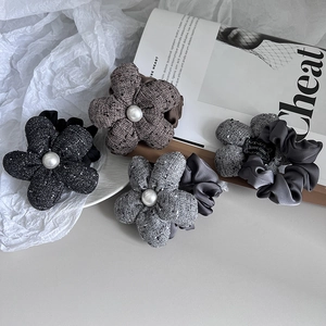 Detail of four handmade fabric flower hair ties with pearl centers in elegant winter colors