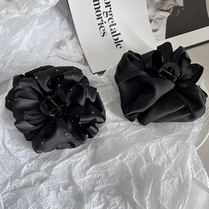 Detail view of two black satin cloud hair claws with sparkling glitter and pleated fabric