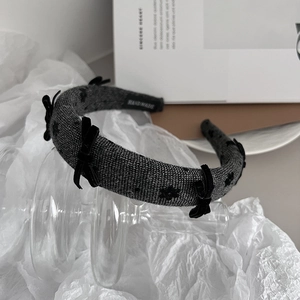 Detail of dark grey knitted headband featuring black velvet bows and handmade label tag