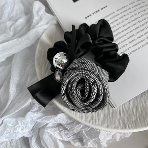 Detail of elegant black satin hair scrunchie with rose floral fabric and jewel accents