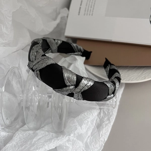 Detail of vintage black satin headband with silver metallic woven texture on paper background