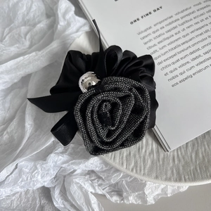 Elegant black tweed and satin scrunchie with a silver metallic bead on a white plate