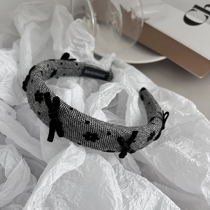 Close-up of handmade bow headband with black and white plaid texture and velvet dots