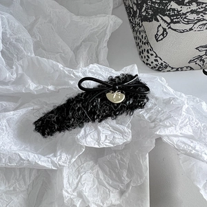 Nahaufnahme der schwarzen Plüsch-Haarspange mit goldenem Herzanhänger auf weißem Papier
