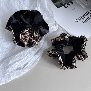 Détail de chouchous en velours noir et imprimé léopard avec une texture douce et brillante