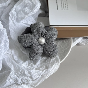 Detail of grey tweed flower hair tie with central pearl on elegant white background