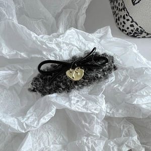 Detailansicht der Haarspange aus schwarzem Tweed mit goldenem Herzanhänger im Detail