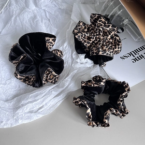 Détail d'un ensemble de chouchous en velours noir et imprimé léopard sur fond blanc
