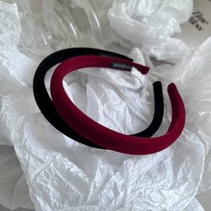 Detailed view of black and burgundy velvet padded headbands with handmade woven labels