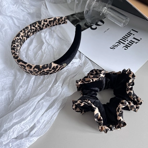 Ensemble serre-tête et chouchou en velours à motif léopard sur un fond d'accessoires chic