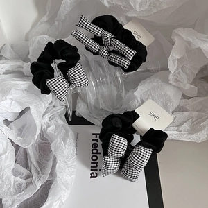 Chouchou avec nœud à carreaux noir et blanc sur un fond d'affichage esthétique